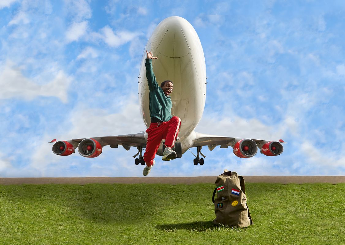 Danser in grasveld springt voor opstijgend vliegveld voor blauwe lucht met wolken