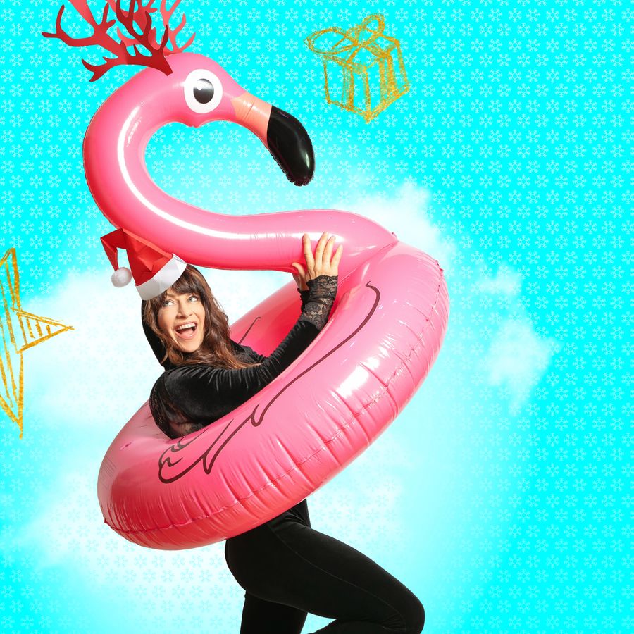 Ellen ten Damme met een kerstmuts op. Ze heeft een roze opblaasflamingo om haar middel.