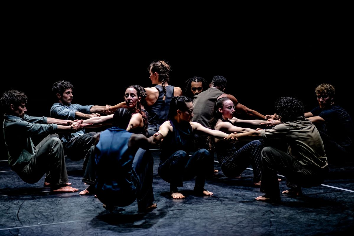 groep dansers in cirkel gehurkd kijkend naar elkaar