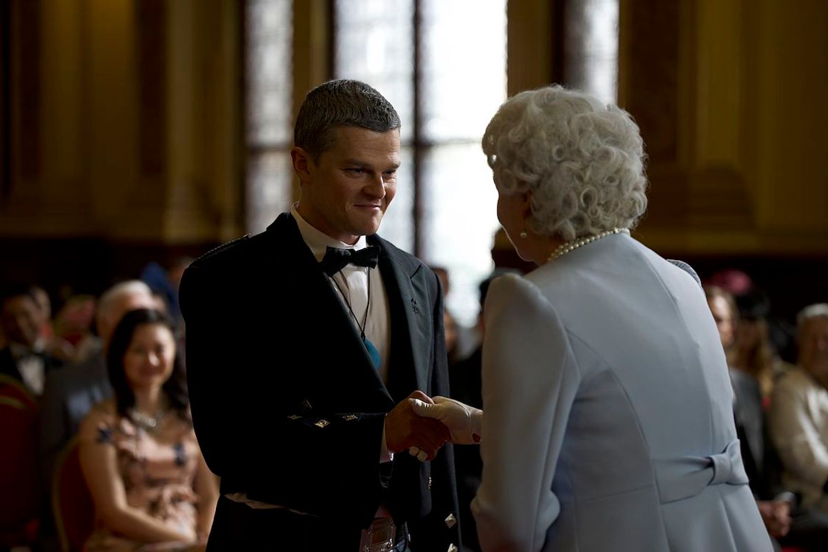 Man die een hand krijgt van koningin Elizabeth in een volle zaal