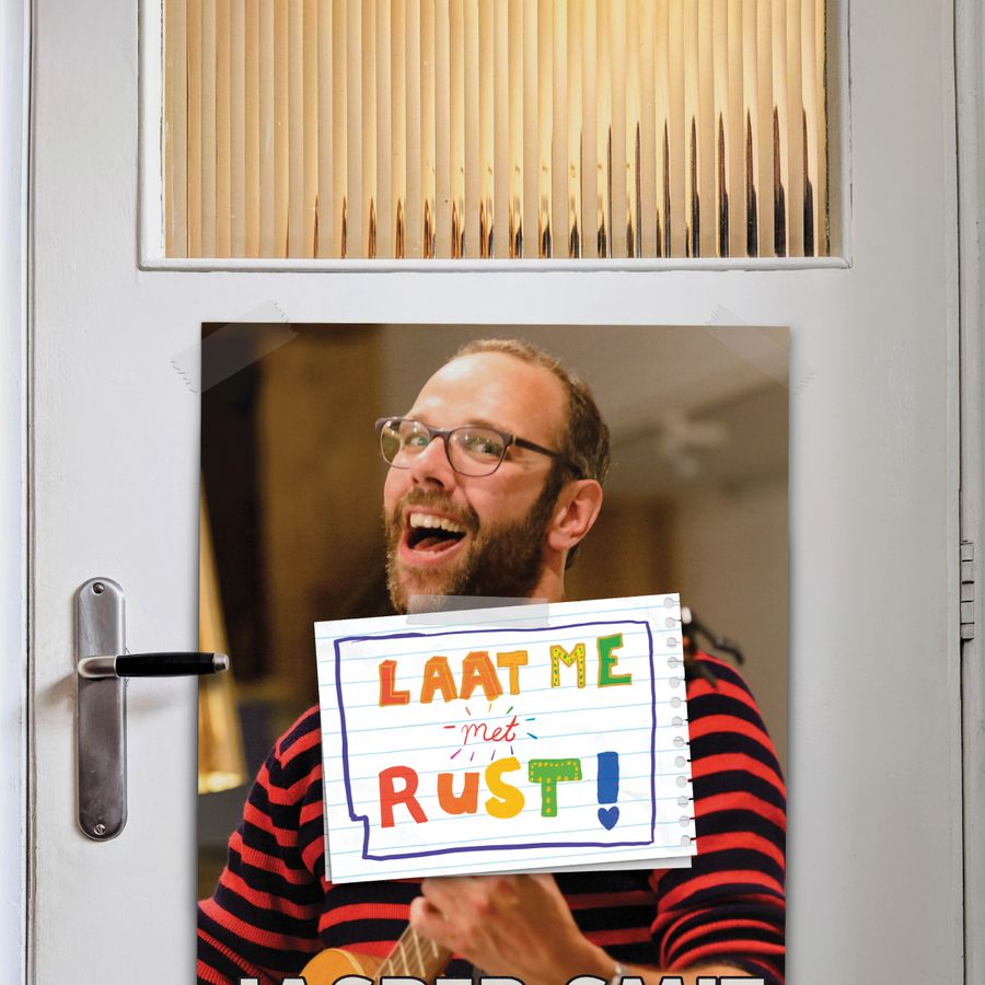 Jasper Smit zit achter een deur, je ziet hem door het glas. Op de deur hangt een briefje met kleurrijk de tekst 'Laat me met rust'