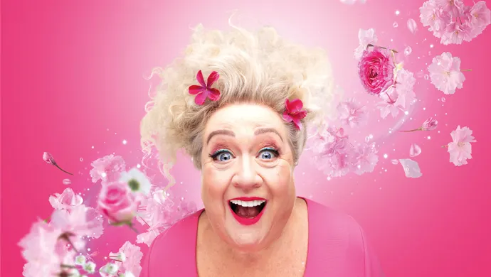 Christel de Laat in roze, met bloemen om haar heen