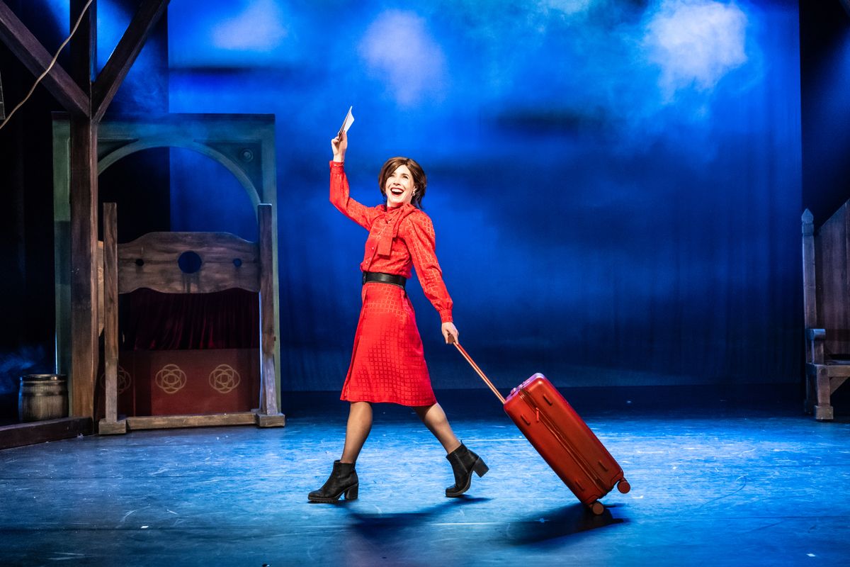 vrouw met rode jurk en rood koffer loopt op podium