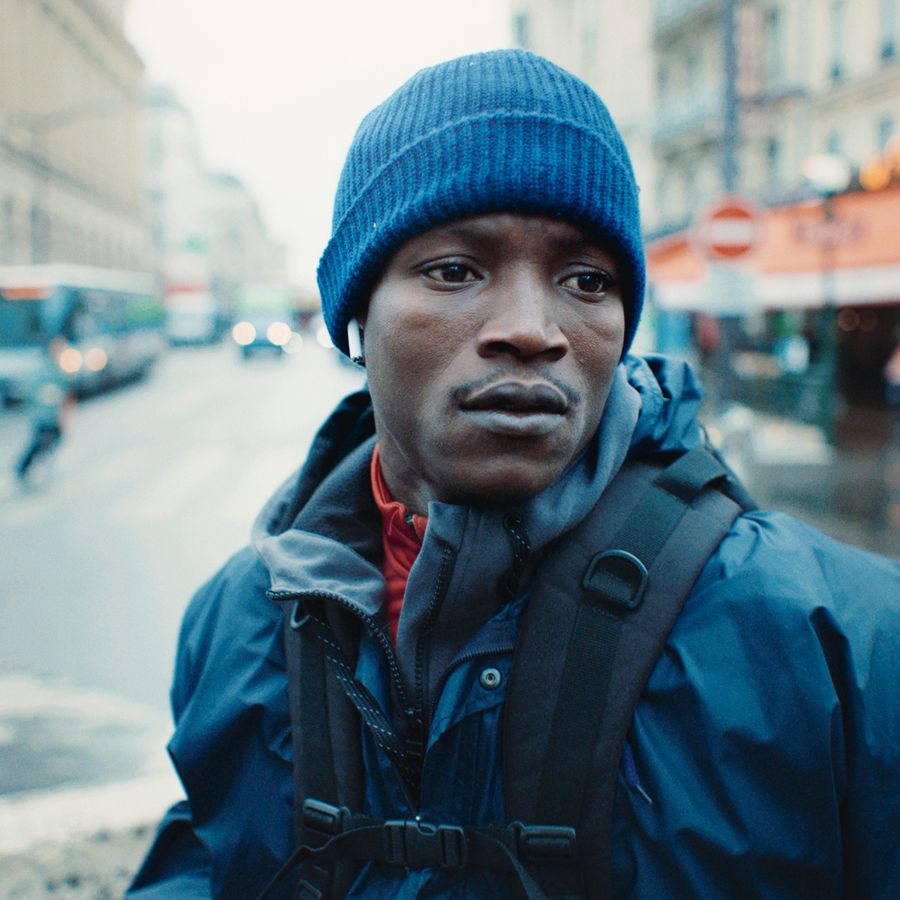 Souleymane in regenpak met muts op in Franse straten