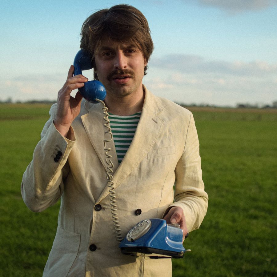 Joost Oomen in grasveld met blauwe telefoon