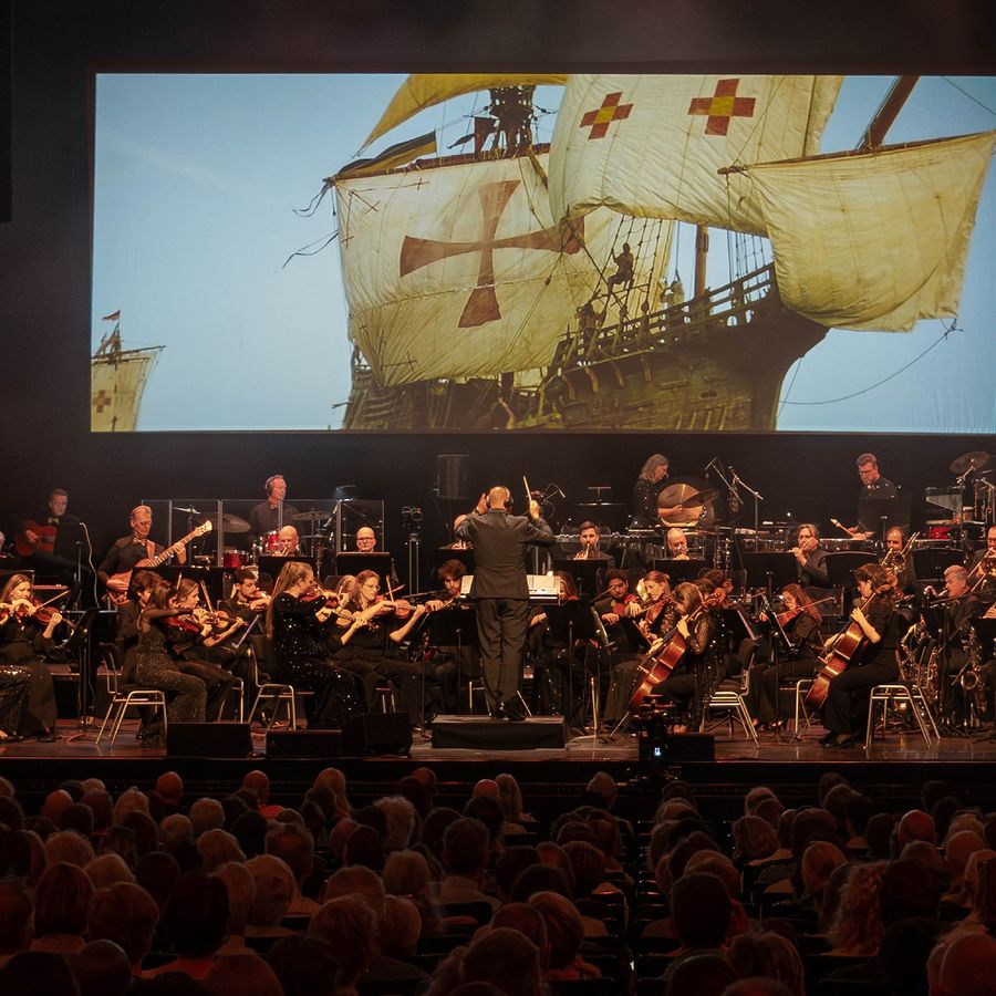 Muzikanten voor een groot scherm met daarop een piratenschip