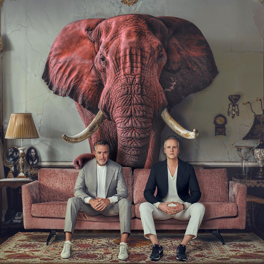 Veldhuis en Kemper op bank, achter hen een grote rode olifant