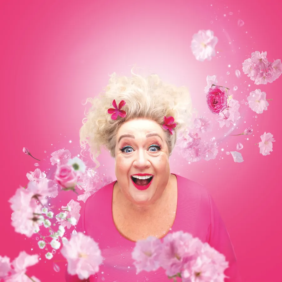 Christel de Laat in roze, met bloemen om haar heen