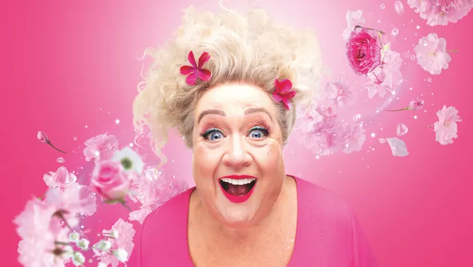 Christel de Laat in roze, met bloemen om haar heen