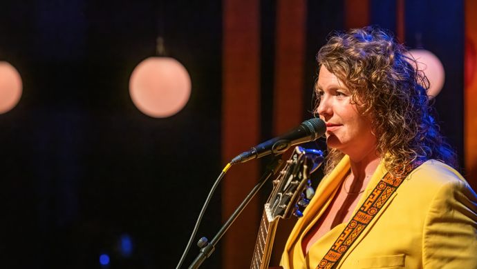 Kiki Schippers in een geel pak met gitaar
