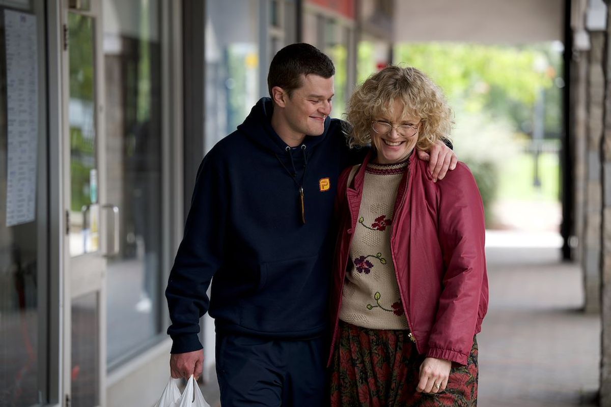 Jongen en vrouw lopen lachend en gearmd