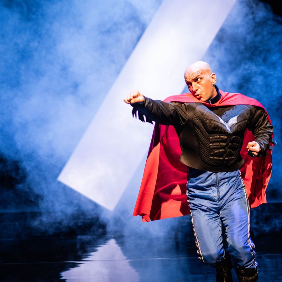 Sadettin K met superman cape en arm naar voren uitgestoken