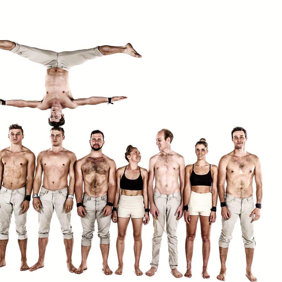 Acrobate naast elkaar, eentje balanceert op zijn kop op iemands hoofd