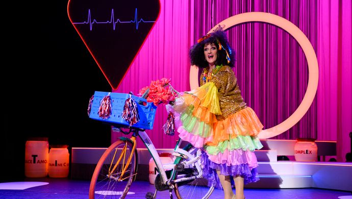 Tineke met fiets in kleurrijke outfit op podium