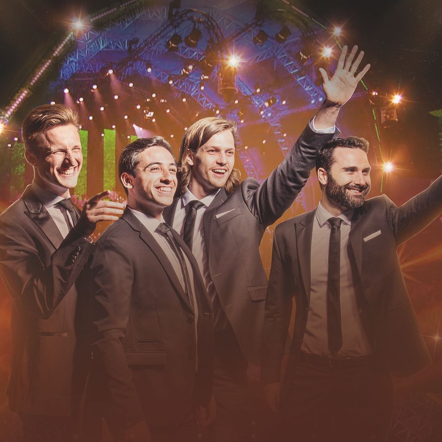 De vier zangers van de Dutch Tenors zwaaien, ze staan voor een oranje uitgelicht podium.