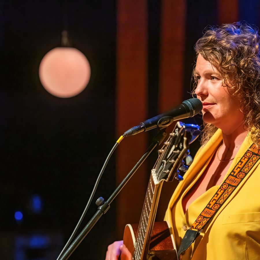 Kiki Schippers in een geel pak met gitaar