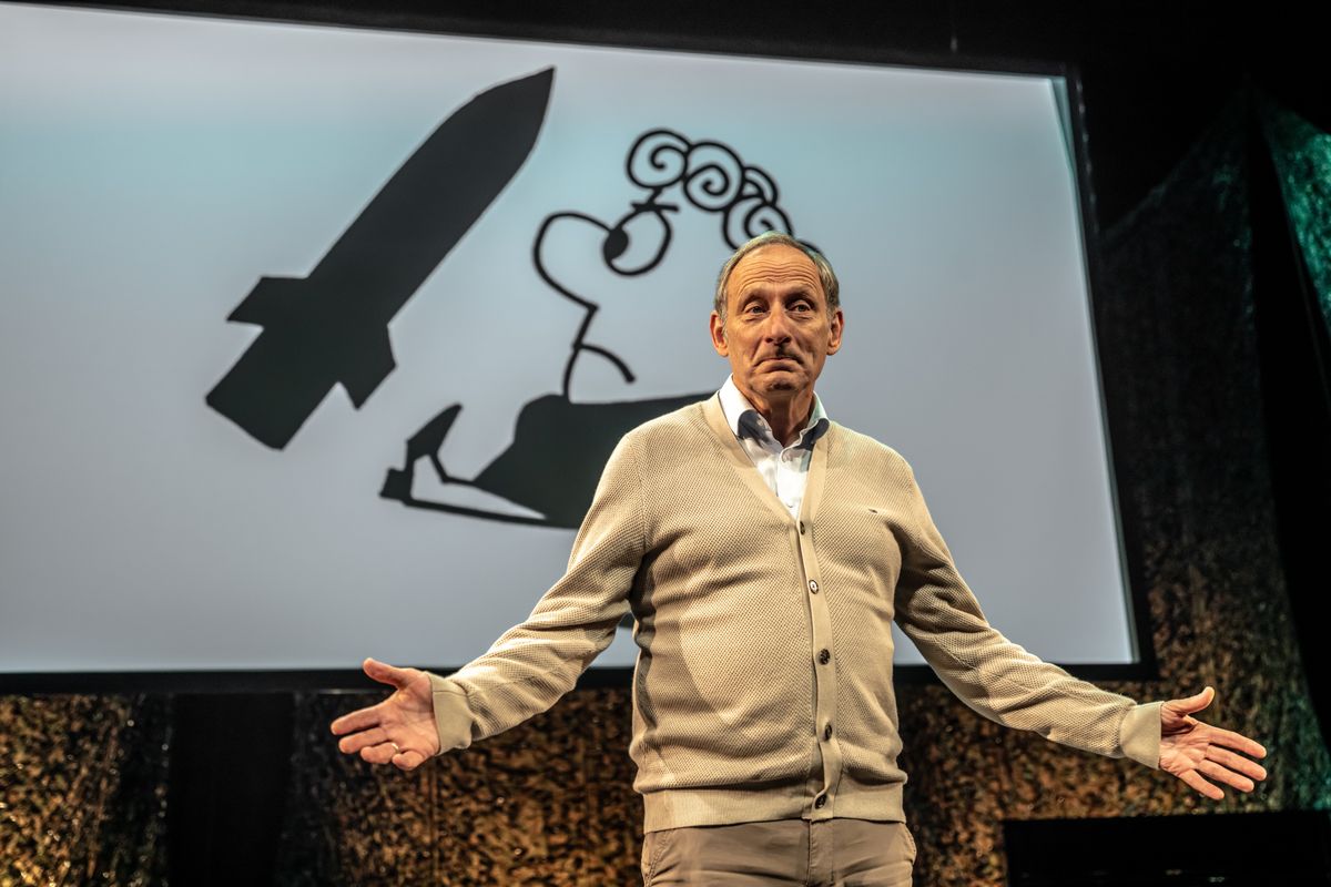 Mart de Kruif op toneel met op achtergrond afbeelding protest tegen kruisraket