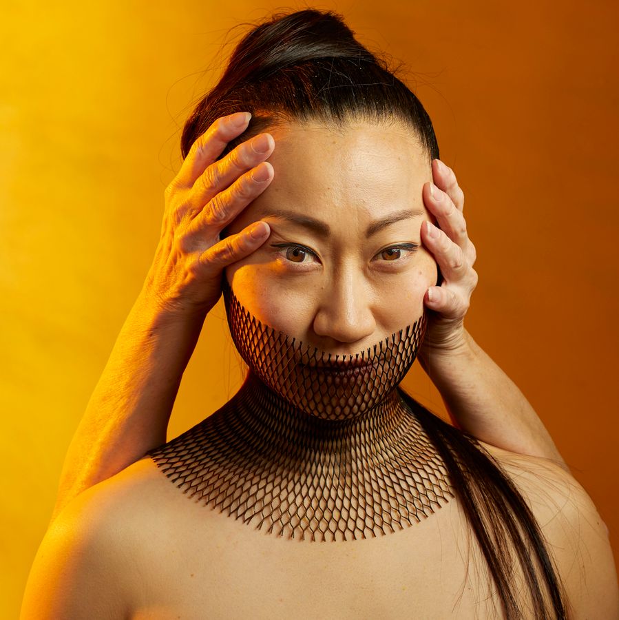 Danser met twee handen op haar hoofd. Gele achtergrond.