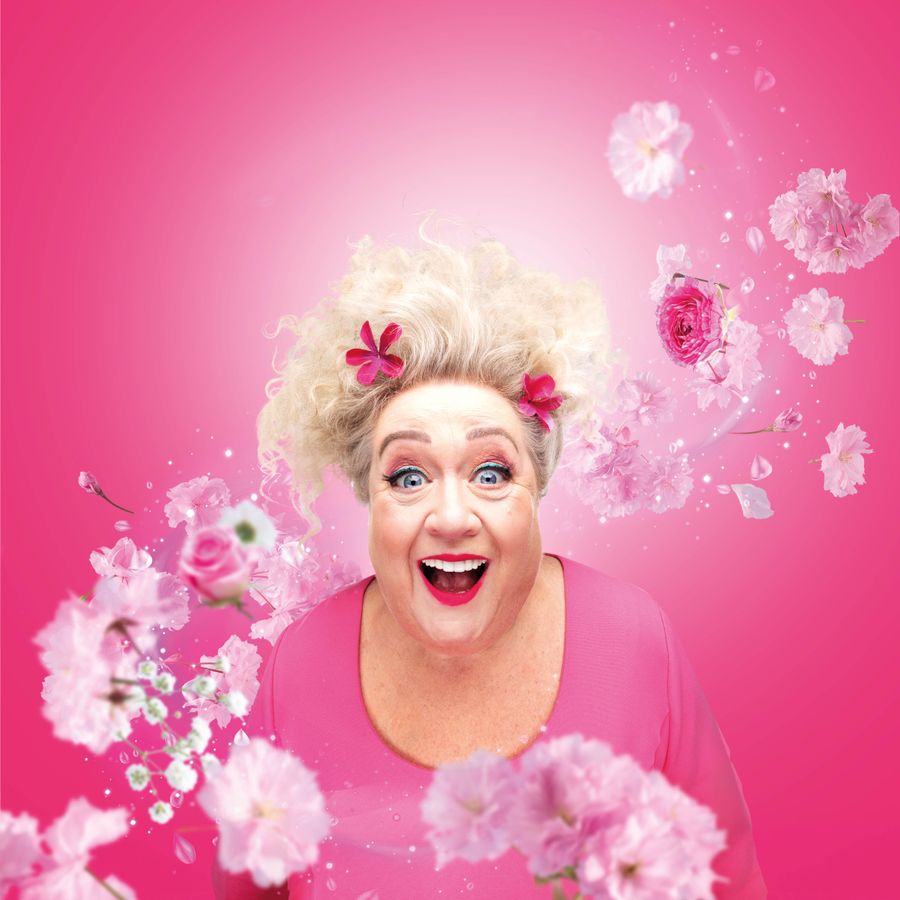 Christel de Laat in roze, met bloemen om haar heen