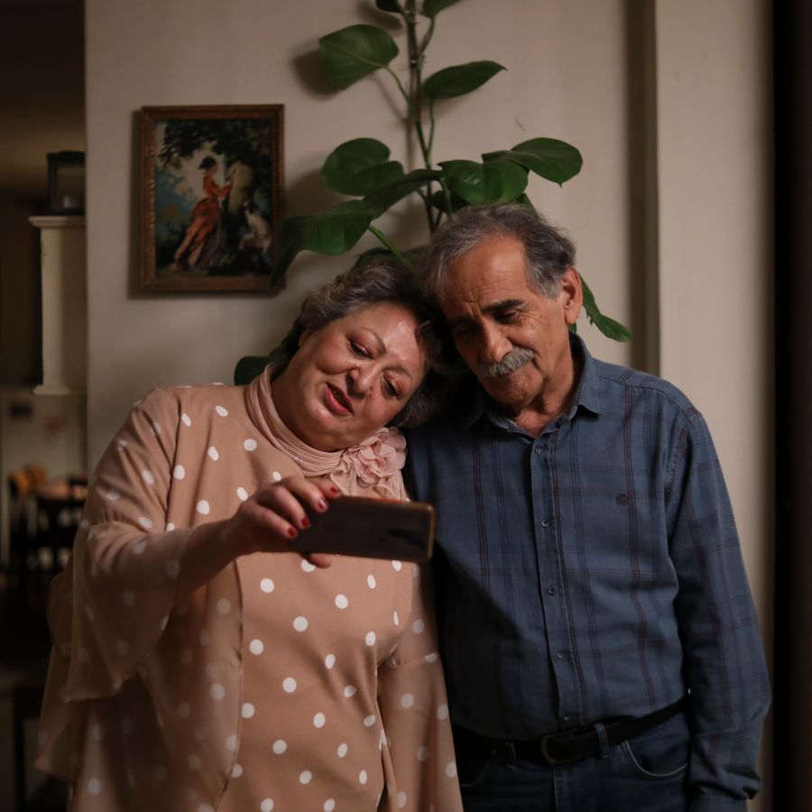 Vrouw legt hoofd op schouder man, ze kijken naar mobieltje