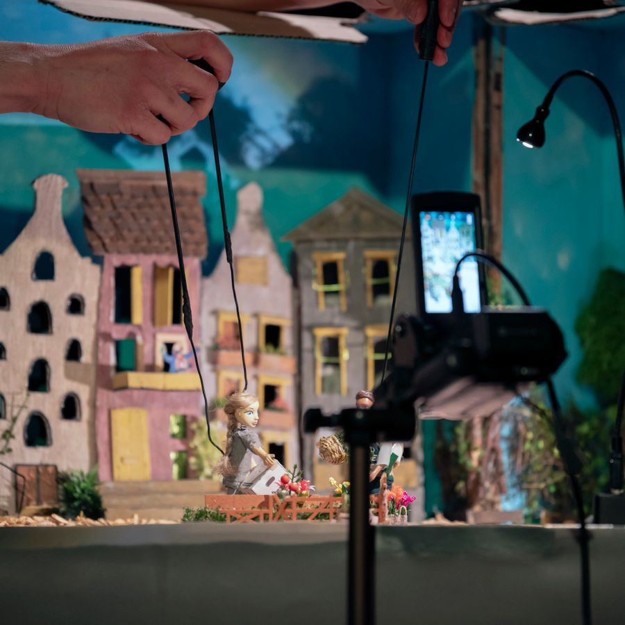 Maquette van kleine huisjes met een mensenhand die een poppetje aan ijzerdraad bestuurt
